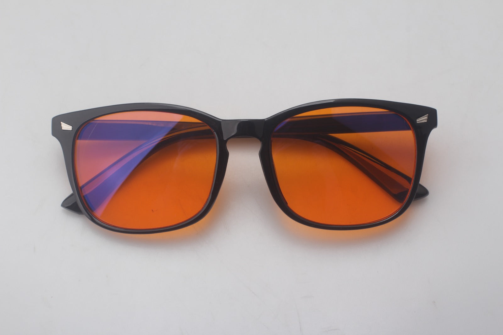 Ingeklapte FocusFlow blauwlichtbril met kenmerkende oranje glazen, ideaal voor onderweg. Compact en krasbestendig design voor eenvoudige opslag en bescherming tegen schadelijk blauw licht.